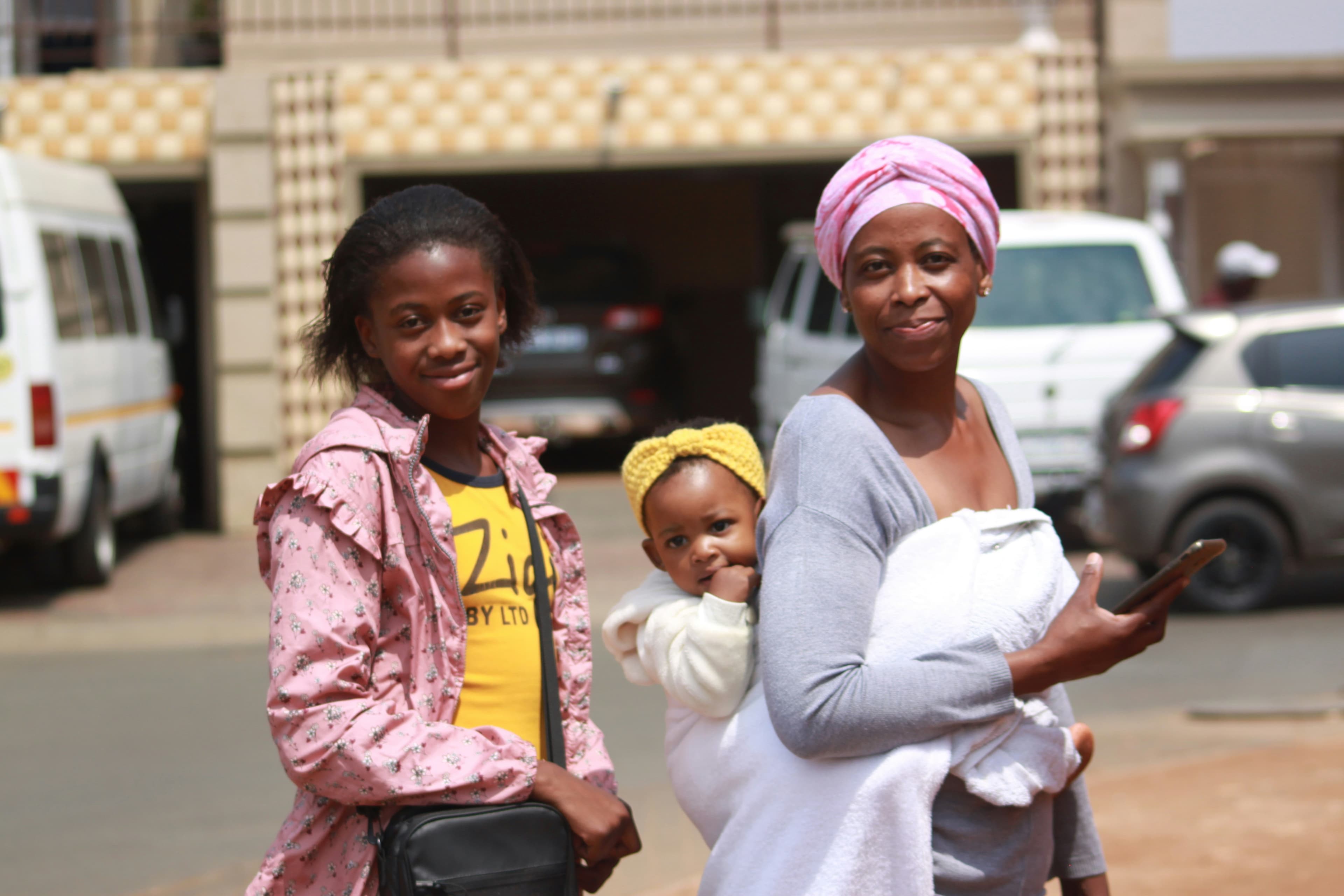 A young woman, a mother and a baby standing together on a street